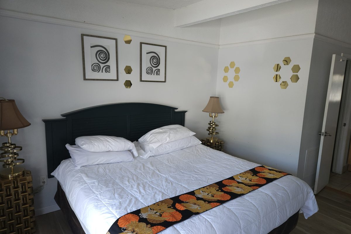 Cozy Queen room at Blazers Lodge with a dark headboard and floral bed runner